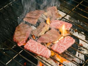 a bunch of meat cooking on a grill at Hotel Asobuba白老 in Shiraoi