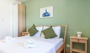a bedroom with a bed with white sheets and green pillows at D&J Apartments in Primošten