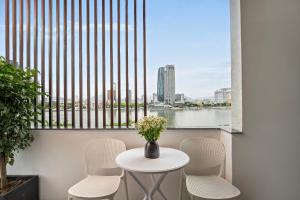a table with chairs and a vase with flowers on a balcony at Ngoc Thuong Hotel & Apartment- Han River View in Danang