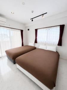 two beds sitting in a room with windows at Luana Uakoko Resort 旧 EmiFull Resort in Chatan