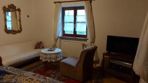 a room with a bed and a tv and a chair at Pension Unterleiten in Ramsau