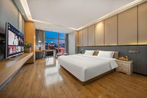 a bedroom with a large white bed and a flat screen tv at ChongQing BackHome Riverview Hotel in Chongqing