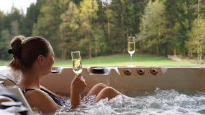 a woman sitting in a tub with two wine glasses at Ferienhof Schmalzgrub in Böbrach
