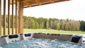 a hot tub in a porch with a view of a field at Ferienhof Schmalzgrub in Böbrach