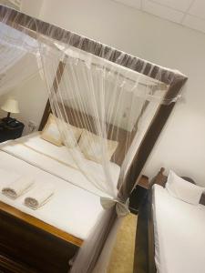 a bed with a mosquito net on top of it at Ceylon Kingsmen Garden - Katunayake Airport Transit Hotels in Negombo