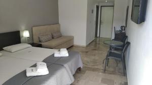 a room with two beds and a couch and a table at Vanisko Hotel in Amoudara Herakliou
