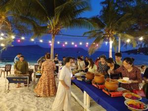 a group of people sitting at a table on the beach at Europe Enchanted Bungalow Koh Rong in Kaôh Rŭng (3)
