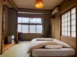 a bedroom with a bed and a large window at 北アルプス麓のゲストハウス林屋 in Omachi