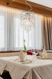 ein Esstisch mit Kronleuchter und Stühlen in der Unterkunft Hotel Olaga in Olang