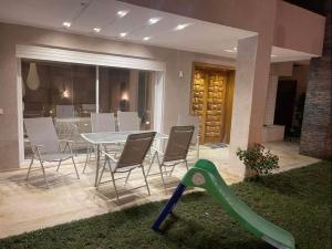 a backyard with a table and chairs and a green slide at Beautiful villa with pool KELIBIA in Kelibia