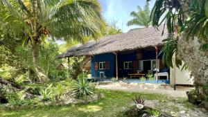 a blue house with a thatched roof at Ravenala Lodge, Bungalow et Maison Ile aux Nattes in Ile aux Nattes