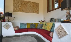 a living room with a red couch with colorful pillows at Bali Firefly BnB in Ubud
