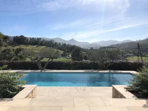 a swimming pool in a garden with mountains in the background at Hergarai in Saint-Jean-le-Vieux