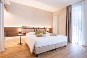 a bedroom with a large white bed and a desk at Alchimia WellResort in Comano Terme
