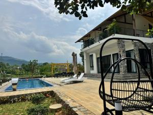 a chair in front of a house with a swimming pool at Flora Garden in Làng Hang