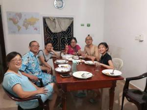 a group of people sitting around a wooden table at Sajee Residence Nilaveli in Trincomalee