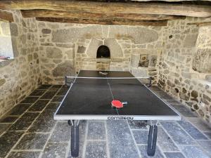 a ping pong table sitting in a stone room with a table at La Borie de Peyrot in Huparlac