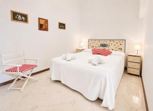 a white bedroom with a large white bed and a chair at Hostdomus - Phil House in Finale Ligure