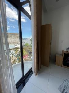 a room with a large window with a view of a balcony at Lya Homestay CMT8 Da Nang in Danang