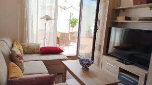 a living room with a flat screen tv and a couch at Apartamento La Camelia in Rosal