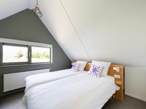 a bedroom with a large white bed with purple pillows at Aan Noordzee Villa Veranda huisdier toegestaan max 2 in Sint Maartensvlotbrug