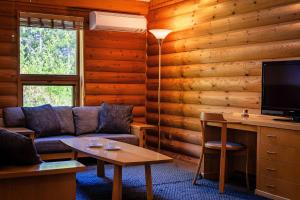 a living room with a couch and a tv at Log Hotel The Maple Lodge in Iwamizawa