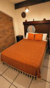 a bedroom with a large bed with an orange blanket at Estadio Azteca Banorte Suites in Mexico City +1 photo