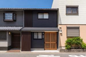 a black house with a brown door on a street at 楓 和室の一棟貸切 最大10名宿泊可能 駅徒歩2分 関西空港直通 in Osaka