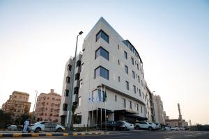 a white building with cars parked in a parking lot at La Terrasse Hotel in Jeddah