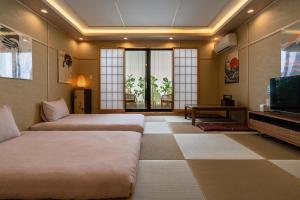a hotel room with two beds and a television at 楓 和室の一棟貸切 最大10名宿泊可能 駅徒歩2分 関西空港直通 in Osaka
