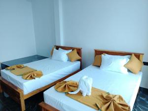 two beds in a room with towels and an animal on them at MSResort in Haputale