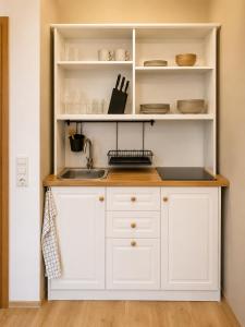 a kitchen with white cabinets and a sink at Falkenstein Loft 55 in Zwiesel +9 photos