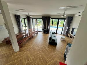 a large living room with a wooden floor and glass windows at Flora Garden in Làng Hang