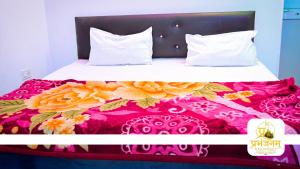 a bed with a pink and white bedspread with flowers on it at Prabhanjanam Residency in Ayodhya