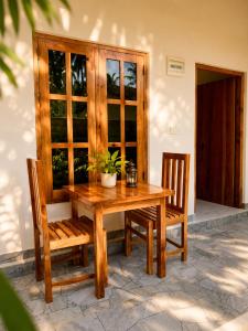 a wooden table with two chairs and a potted plant at Royal Palms Resort in Arugam Bay