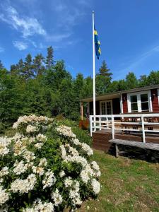 ein Haus mit einem Fahnenmast und Blumen davor in der Unterkunft Magical hide-away in the forest in Trensum + 11 Fotos