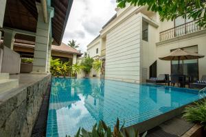 a swimming pool in front of a house with an umbrella at Kevans Casa in Mahiyangana