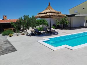 a swimming pool with an umbrella and chairs and a patio at Rocky in Razvala