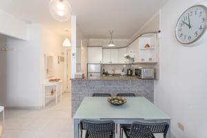 a kitchen with a table and a clock on the wall at Casa Cabana in El Médano +12 photos