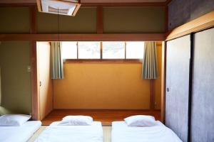 two beds in a room with a window at Knot Kyonan in Katsuyama