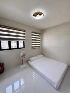 a white bedroom with a bed and windows at Idesia Lipa Custodio Suites in Lipa +10 photos
