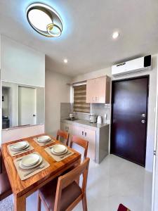 a kitchen with a wooden table with chairs and a dining room at Idesia Lipa Custodio Suites in Lipa