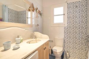 a bathroom with a sink and a toilet and a mirror at Tinos Sunset House in Tinos +15 photos