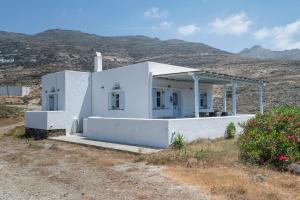 a white house with mountains in the background at Tinos Sunset House in Tinos
