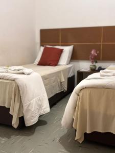 a bedroom with two beds with white sheets at Six's Hotel in Jacareí +18 photos