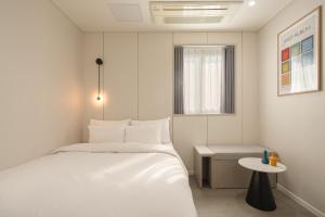 a white bedroom with a bed and a table at No25 Hotel Chuncheon Cityhall in Chuncheon +33 photos