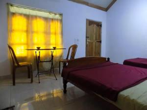 a bedroom with a bed and a table and chairs at Sajee Residence Nilaveli in Trincomalee