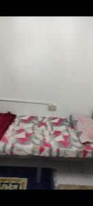 a bed with red and white sheets on it at Living room in Muscat