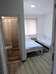 two beds in a room with a shower and a toilet at air&wizz II in Dubrave Gornje