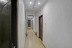 a hallway with white walls and a hallway with two plants at Hotel O Dps Inn in Allahābād